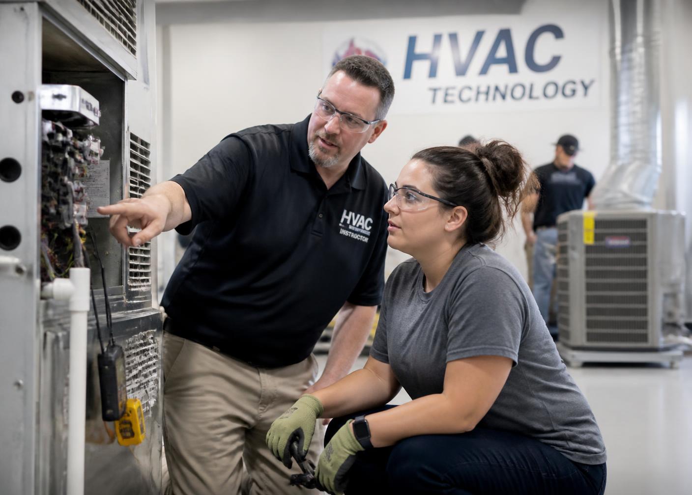 Adult student learning HVAC systems with an instructor in a training lab